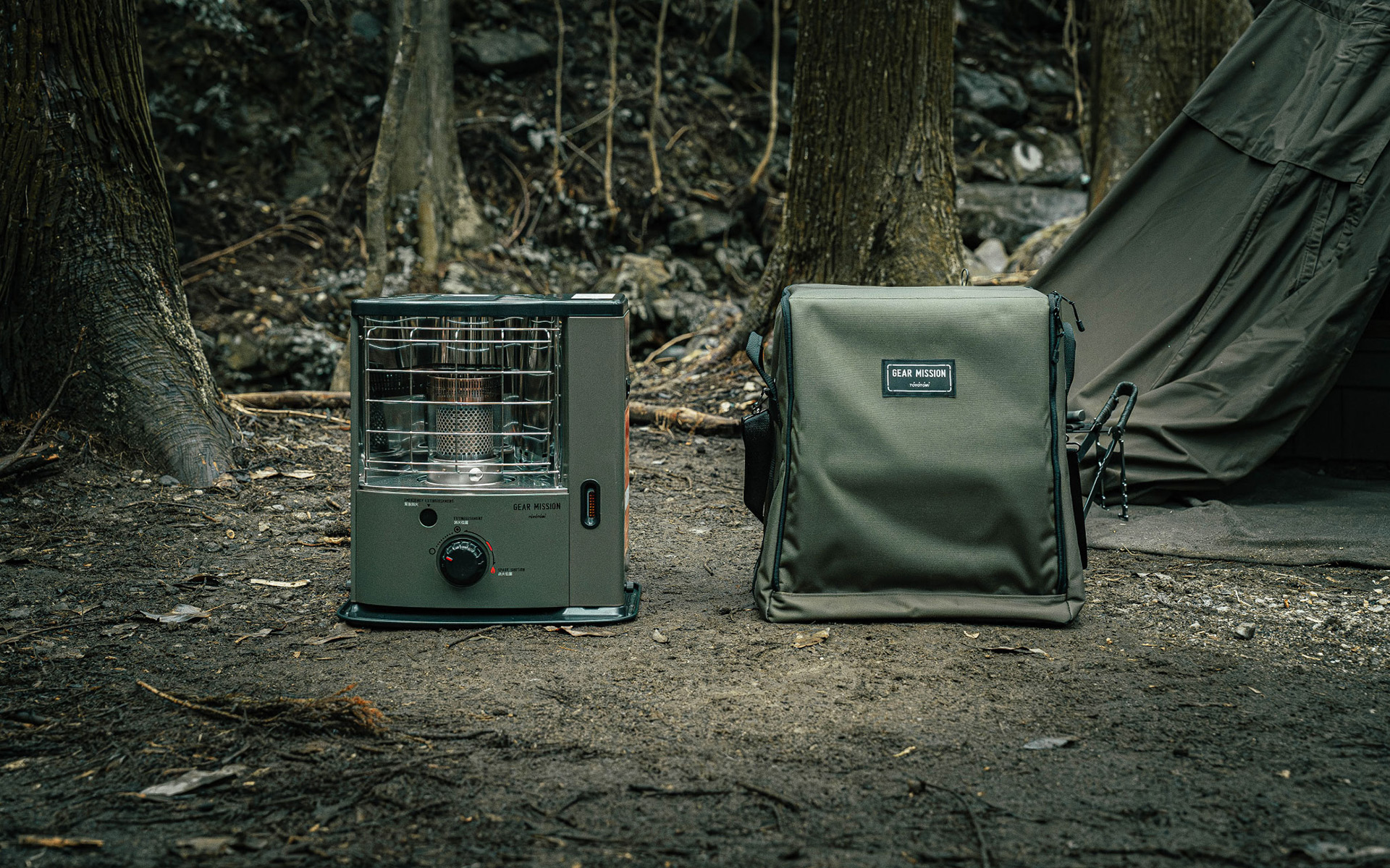 Toyotomi GEAR MISSION heater next to its carrying bag at a camping site, showcasing portable heating for outdoor adventures.