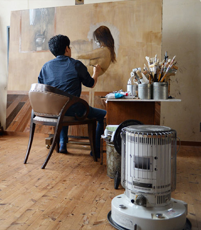 El calentador de tipo redondo de Toyotomi está calentando la habitación de un pintor que está pintando un cuadro grande