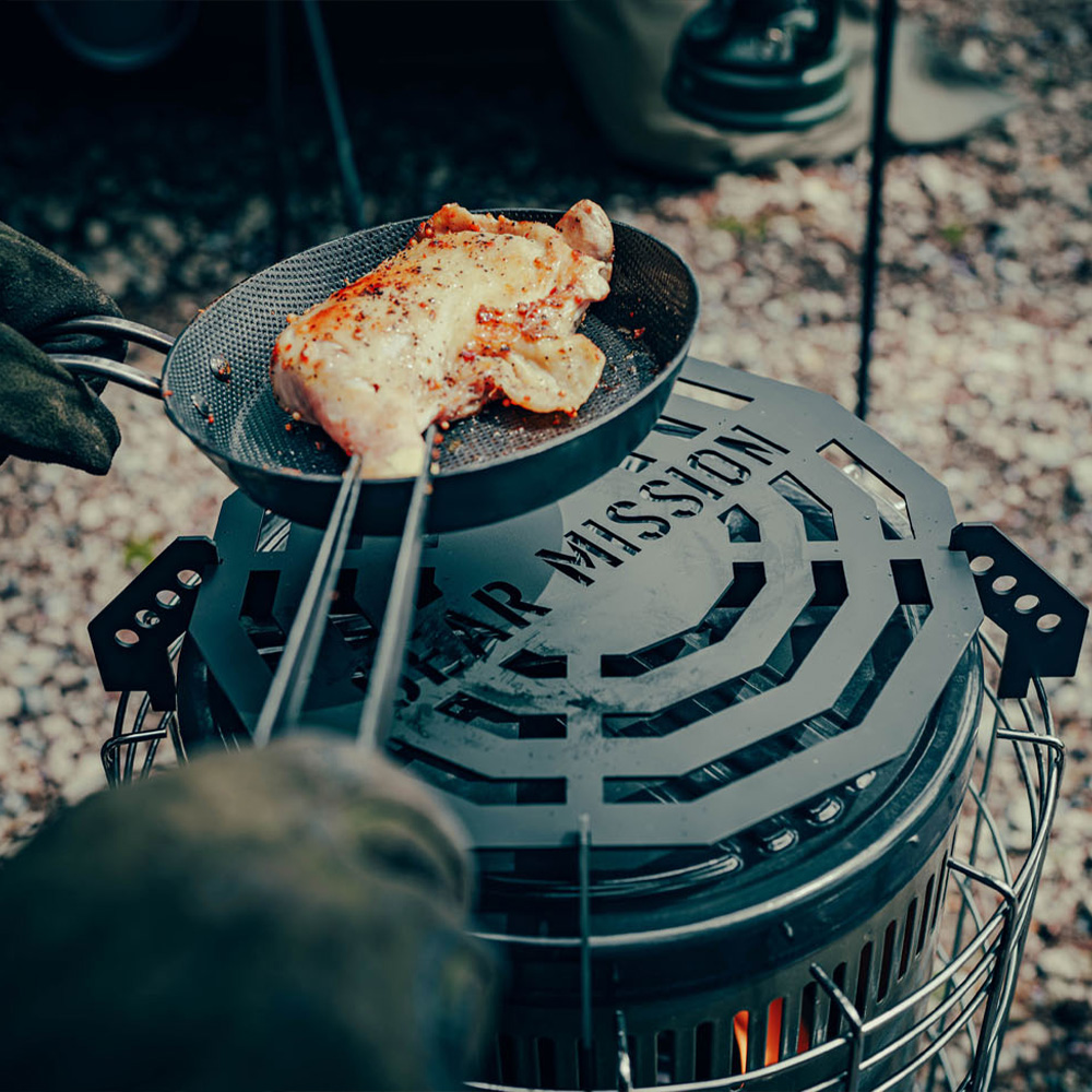 Toyotomi GEAR MISSION cooking plate being used to cook chicken on top of a GEAR MISSION round type paraffin heater.
