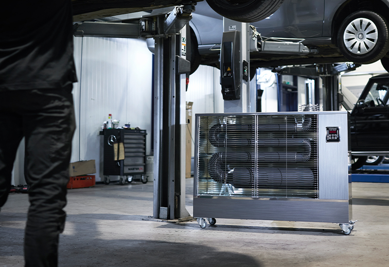 Toyotomi Infrarotheizung TIB-16 heizt einen Mechaniker in einer Autowerkstatt, der an einem Auto arbeitet.