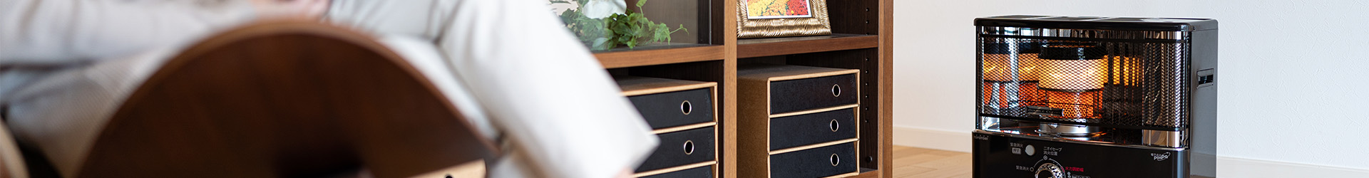 Toyotomi wick heater in a living room showing the burner and heating a girl who is reading a book