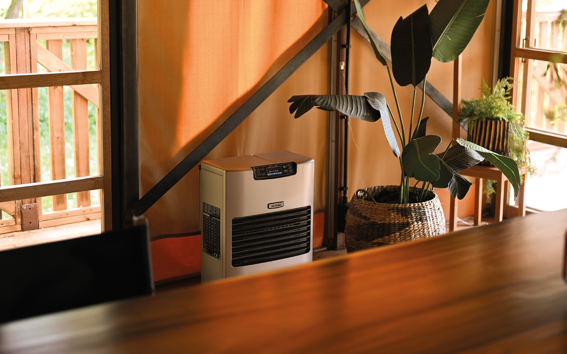 Toyotomi Europe round type paraffin heater OMNI, with two people around it enjoying the warmth that comes from the Toyotomi heater