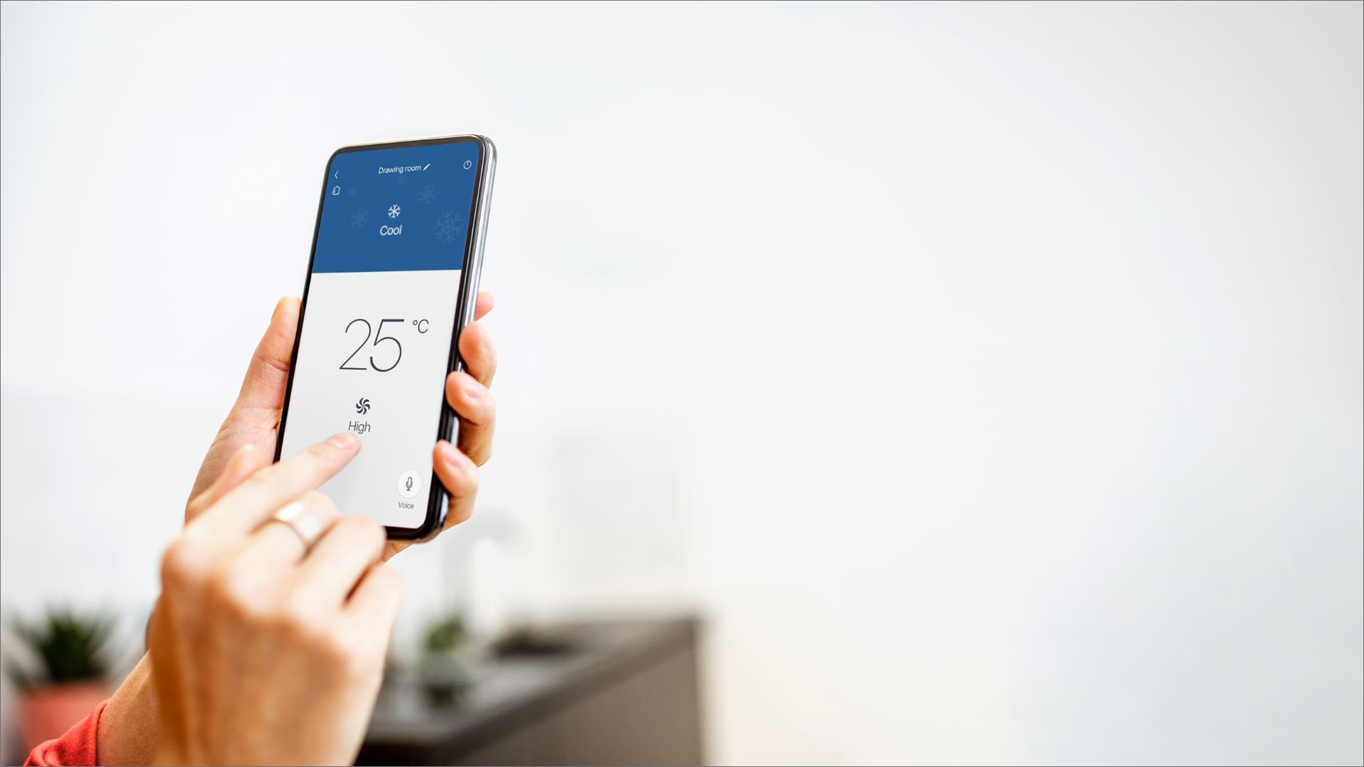Person adjusting a smart thermostat via smartphone app for home climate control.